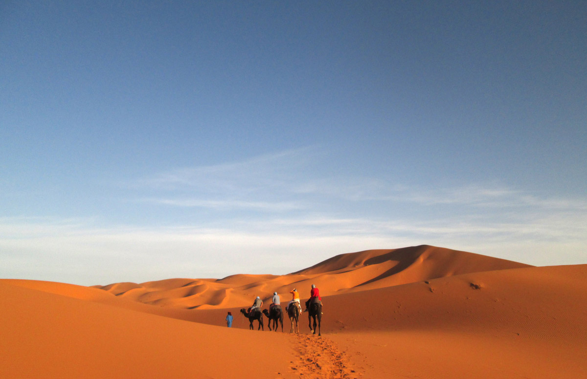 people on camels in the sand dunes in the Sahara Desert near Merzouga Morocco